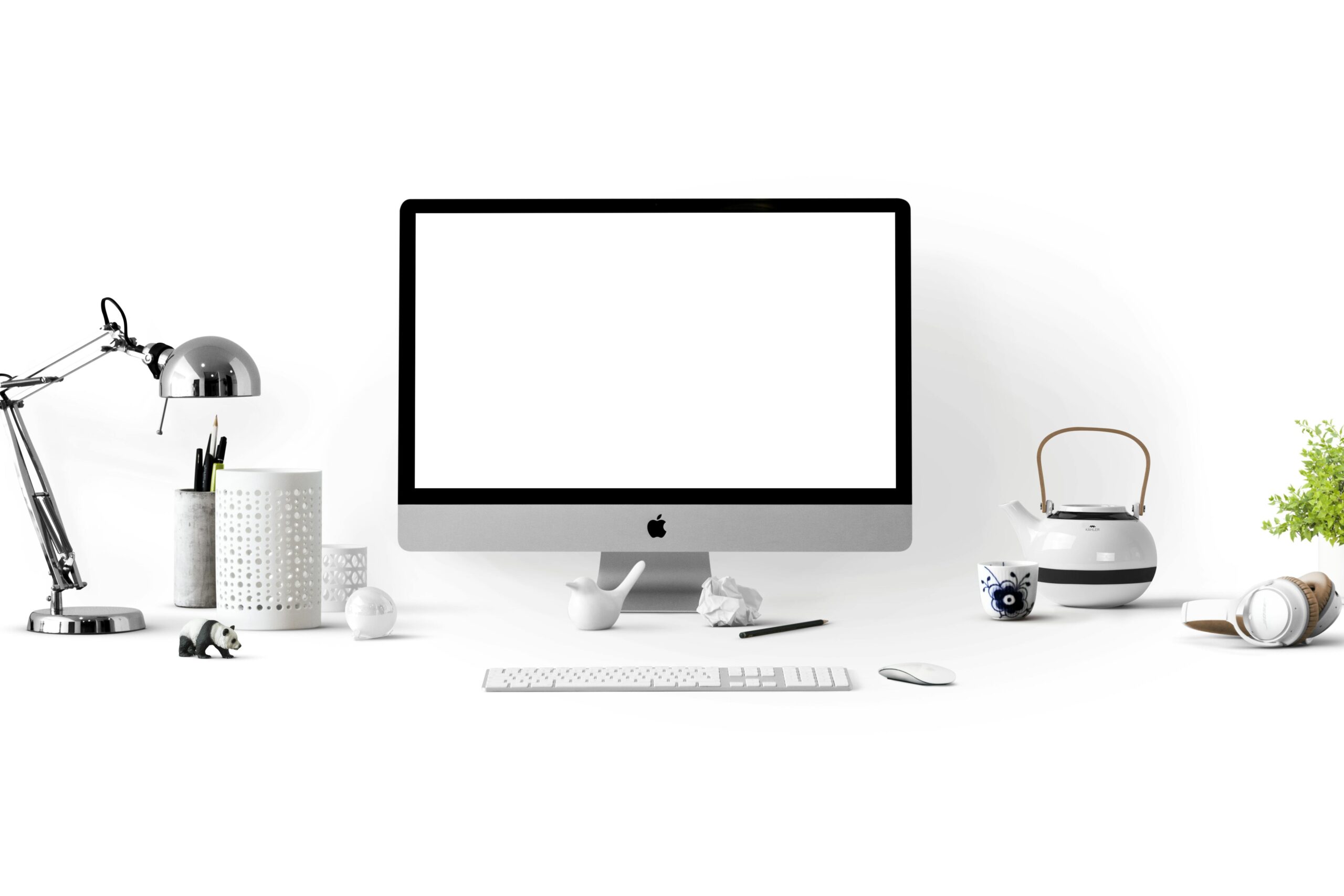 Minimalist office desk with an iMac, lamp, and stationary, perfect for tech backgrounds.